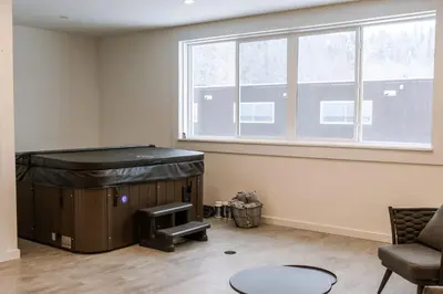 a room with a hot tub and a chair and a window at Revy To Go - Unique 2-Bedroom Condo in Revelstoke