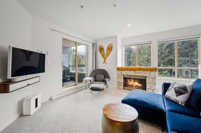 a living room with a blue couch and a fireplace at 1BR plus King Murphy Bed in Tyndall Stone Lodge, Village Location, Pool and Hot Tub, Fireplace in Whistler
