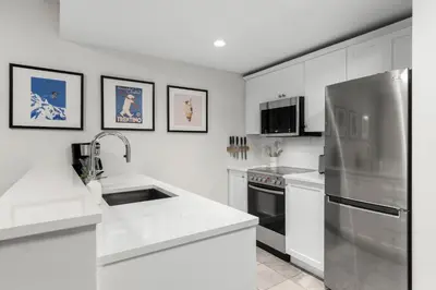 a kitchen with white cabinets and a stainless steel refrigerator at 1BR plus King Murphy Bed in Tyndall Stone Lodge, Village Location, Pool and Hot Tub, Fireplace in Whistler