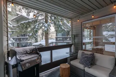 a screened in porch with a grill and a couch at 1BR in Powderview, Creekside, Bright and Cozy, Private Ski Storage, Fireplace, Free Parking in Whistler