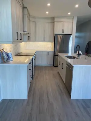 a kitchen with white cabinets and stainless steel appliances at Cozy House In Airdrie in Airdrie