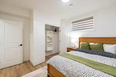 a white bedroom with a bed and a window at Free Parking - Beautyrest Beds - Heated Bath Floor in Calgary