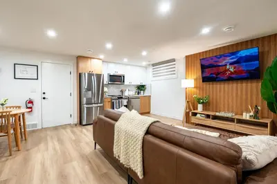 a living room with a couch and a kitchen at Free Parking - Beautyrest Beds - Heated Bath Floor in Calgary