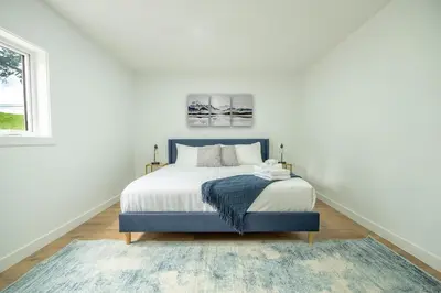 a white bedroom with a bed and a window at The Pines on 15th Ave - Hot Tub, BBQ in Invermere