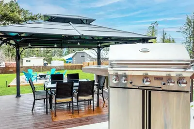 a grill on a deck with chairs and a table at The Pines on 15th Ave - Hot Tub, BBQ in Invermere