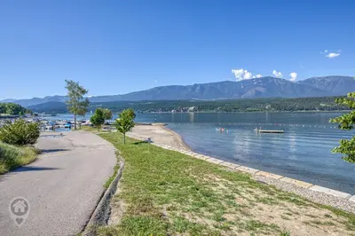 a road next to a lake with mountains in the background at Akiskinook Resort by StayIn in Windermere