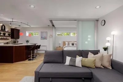 a living room with a gray couch and a kitchen at Cozy 1BR BSMT Escape Large Free Parking in Coquitlam