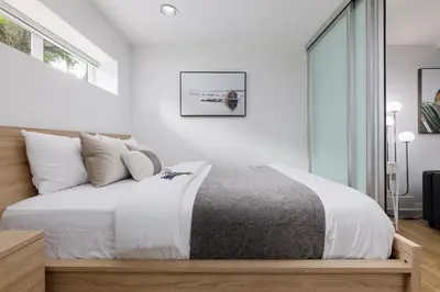 a bedroom with a bed with white walls and a window at Cozy 1BR BSMT Escape Large Free Parking in Coquitlam
