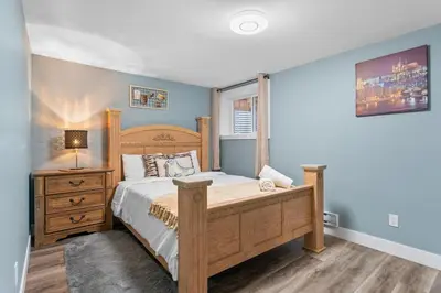 a bedroom with a bed and a dresser with a lamp at Private Family Entertainer's Suite in Calgary