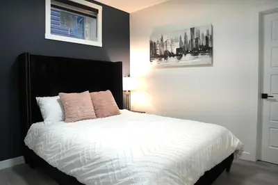 a bedroom with a bed with white sheets and pink pillows at The Cozy Nook of Seton in Calgary
