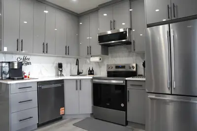 a kitchen with white cabinets and stainless steel appliances at The Cozy Nook of Seton in Calgary