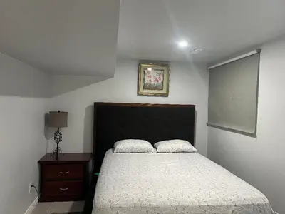 a bedroom with a large bed and a nightstand with a bed sidx sidx sidx at Cozy and comfy 1 BEDROOM basement suite at Cougar ridge SW Calgary in Calgary