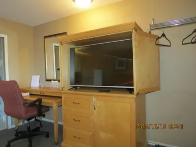 an office with a desk with a large television on a wooden cabinet at Bulkley Valley Motel in New Hazelton