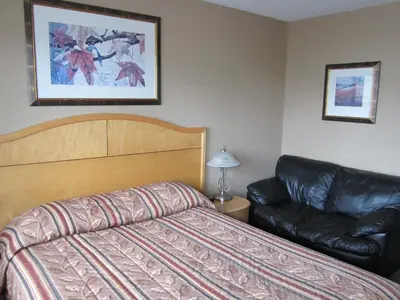 a bedroom with a bed and a leather couch at Bulkley Valley Motel in New Hazelton