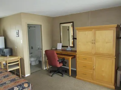 a hotel room with a desk and a bed and a bedroom at Bulkley Valley Motel in New Hazelton