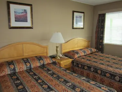 a hotel room with two beds and a lamp at Bulkley Valley Motel in New Hazelton