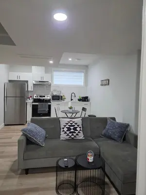 a living room with a couch and a kitchen at Cozy Up in Edmonton