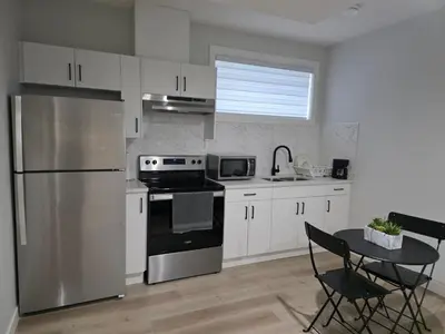 a kitchen with white cabinets and a stainless steel refrigerator at Cozy Up in Edmonton