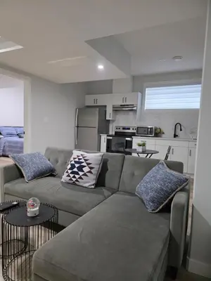 a living room with a couch and a kitchen at Cozy Up in Edmonton