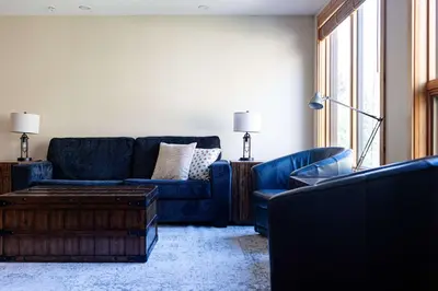 a living room with a blue couch and a table at Creekside 2-Bedroom Condo in Canmore