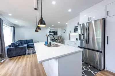 a kitchen with white cabinets and a refrigerator at Valley Villa Spacious 5BD Getaway! Sleep 12, 1hr to Banff, 40 Mins Canmore, 5 mins to WinSport & Olympic park in Calgary