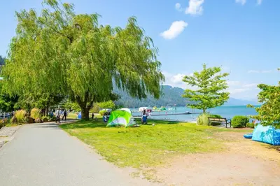 a park with tents on the grass near the water at The Riverbend Modern Studio at Harrison Lake in Harrison Hot Springs