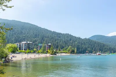 a beach with people on the shore of a lake at The Riverbend Modern Studio at Harrison Lake in Harrison Hot Springs