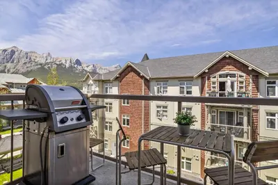a grill and a table on a balcony with a house at Mountain Views Balcony and Free Parking in Canmore