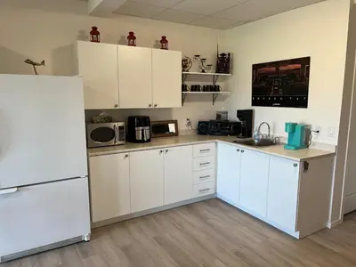 a kitchen with white cabinets and a refrigerator at The Flight Line in Calgary