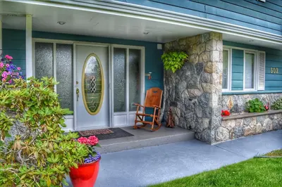 a front door of a house with a chair on the porch at Sunny Shuswap B&B in Chase