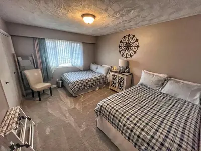 a bedroom with two beds and a chair and a window at Sunny Shuswap B&B in Chase