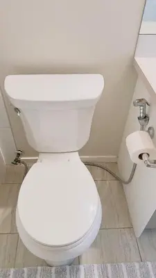 a white toilet in a bathroom with a roll of toilet paper at Calgary Airport Getaway Spacious 3BR Full Home in Calgary