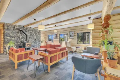 a living room with furniture and a stone wall at HI Nordegg - Hostel in Nordegg