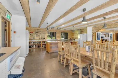 a kitchen with wooden ceilings and wooden tables and chairs at HI Nordegg - Hostel in Nordegg