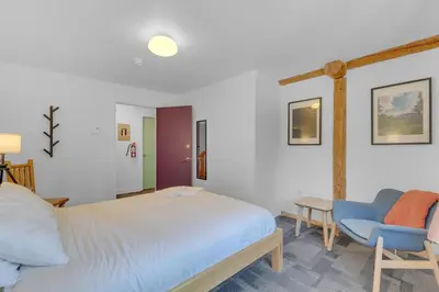 a bedroom with a bed and a blue chair at HI Nordegg - Hostel in Nordegg
