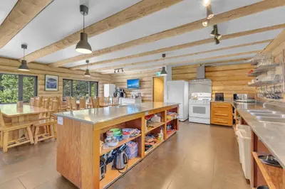 a large kitchen with wooden walls and a large island at HI Nordegg - Hostel in Nordegg