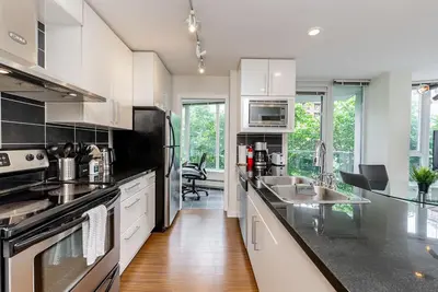 a kitchen with white cabinets and a black counter top at Spacious Downtown Condo with Pool Gym & Parking in Vancouver