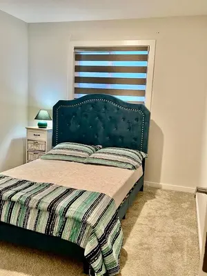 a bedroom with a bed with a green headboard at single house in Edmonton