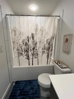 a bathroom with a toilet and a shower curtain with trees at single house in Edmonton