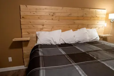 a bedroom with a wooden headboard and a bed with pillows at Rocky Mountain Gem - One Level 750 sq ft - Hot Tub - Quiet Condo - Self Check-In - Free Parking - BBQ Fire Pit Area in Canmore