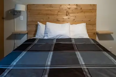 a large bed with a wooden headboard in a room at Rocky Mountain Gem - One Level 750 sq ft - Hot Tub - Quiet Condo - Self Check-In - Free Parking - BBQ Fire Pit Area in Canmore