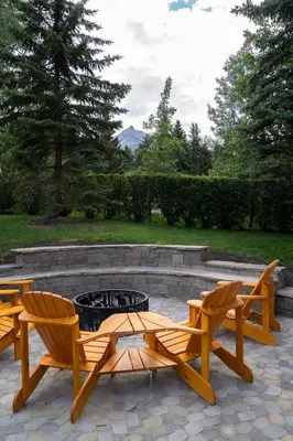 a fire pit with three wooden chairs and a table and benches at Rocky Mountain Gem - One Level 750 sq ft - Hot Tub - Quiet Condo - Self Check-In - Free Parking - BBQ Fire Pit Area in Canmore