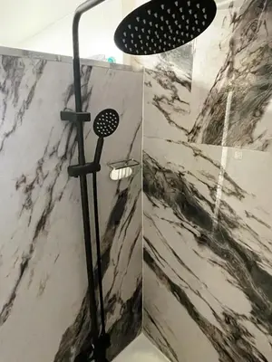 a shower in a bathroom with a marble wall at Shiraz Suite in Calgary