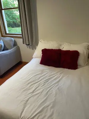 a white bed with a red pillow on it at Cabernet Sauvignon Escape in Calgary