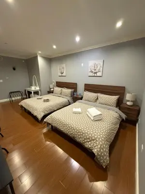 two beds are in a room with wooden floors at Peaceful & Cozy Home with 3 rooms, SHARED Bathrooms and SHARED Common Space in Vancouver