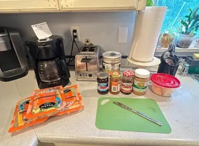 a kitchen counter with a green cutting board and a pen at Comfy Sleep In Fraser Valley With Breakfast in Abbotsford