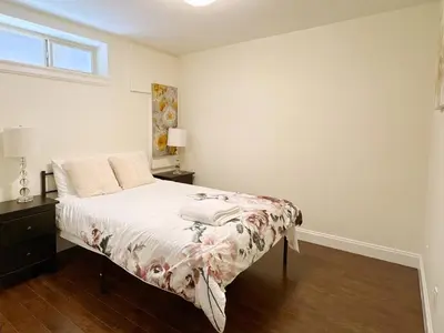 a bedroom with a bed with a floral bedspread at Bright 1-Bedroom Garden Suite, Sleeps 4, Near Downtown & YVR in Vancouver