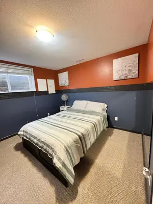 a bedroom with a bed with an orange wall at Peaceful House with Backyard in Langley