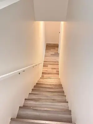 a staircase in a room with white walls and wooden floors at Cozy Corner - 1 bedroom suite - 15 mins from airport in Calgary