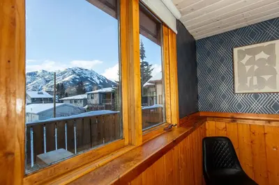 a room with a balcony with a view of mountains at Mountain View Retreat in the heart of Banff - Massive House Sleeps 23 in Banff
